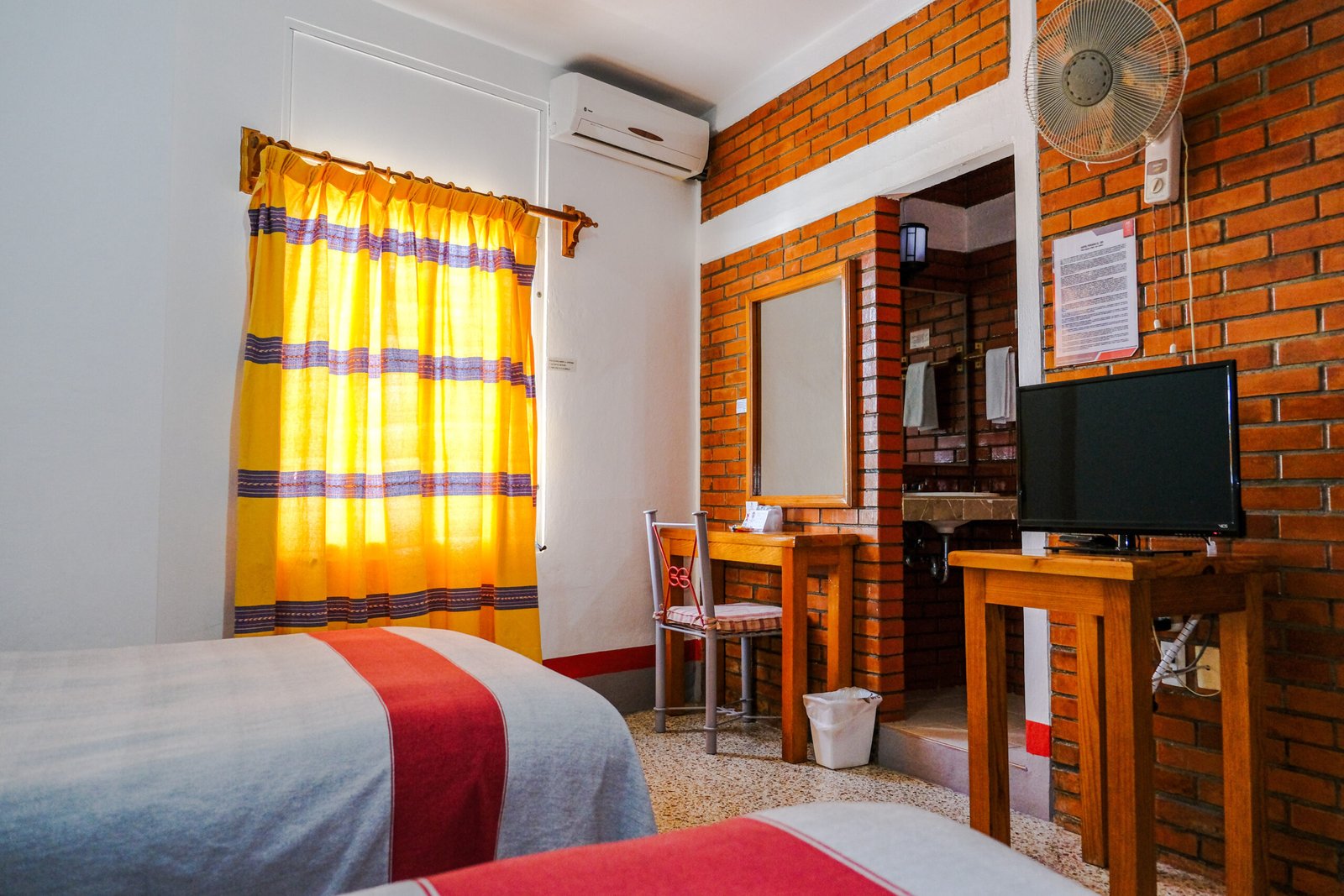 Habitación con muro de ladrillo, cortina amarilla y escritorio