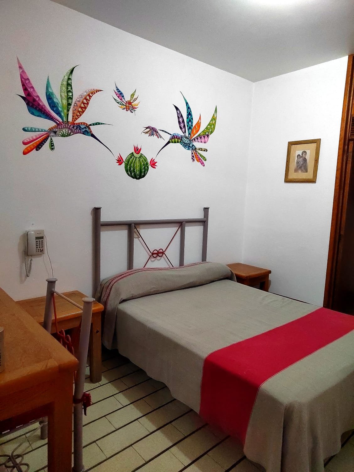 Cama, escritorio y mural de colibríes