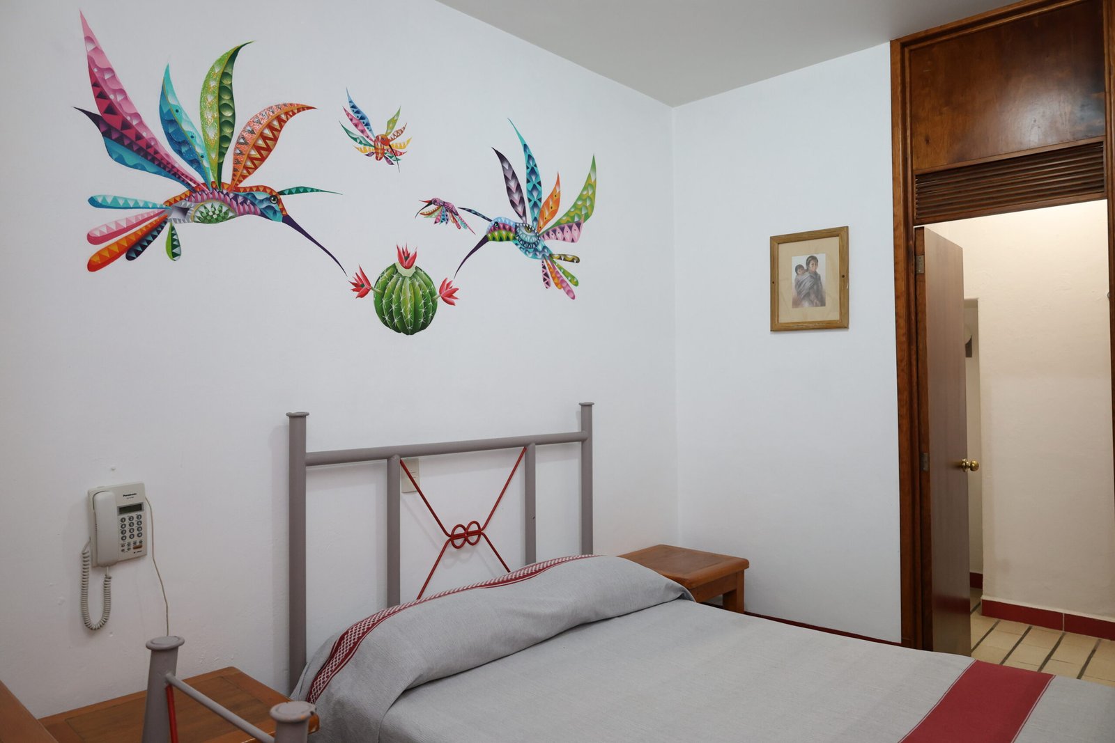 Cama y mural de colibríes en la habitación sencilla