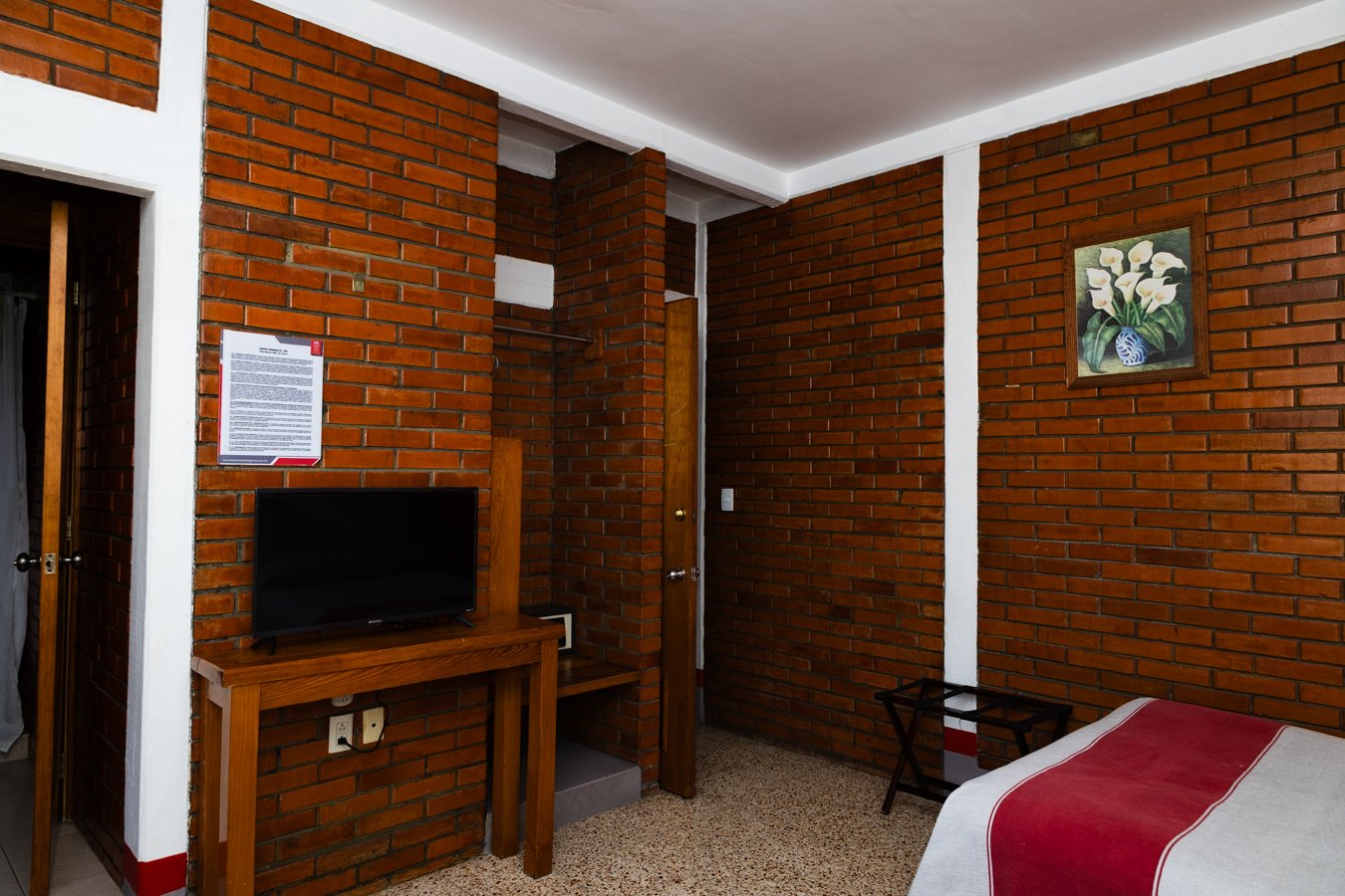 TV sobre escritorio de madera y puerta al baño